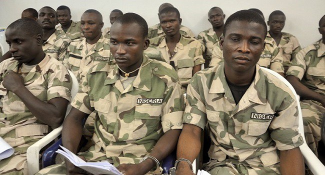 Some of 59 Nigerian soldiers facing trial on charges of mutiny and conspiracy to commit mutiny over claims that they refused to fight Boko Haram militants sit handcuffed on October 15, 2014 in the military courtroom in Abuja. The soldiers, all members of the 111th Special Forces Battalion, all pleaded not guilty in court. They are also accused of refusing to deploy in August to recapture the towns of Yelwa, Bellabulini and Dambo in Borno state from Boko Haram, according to the charge sheet. AFP PHOTO / STRINGER